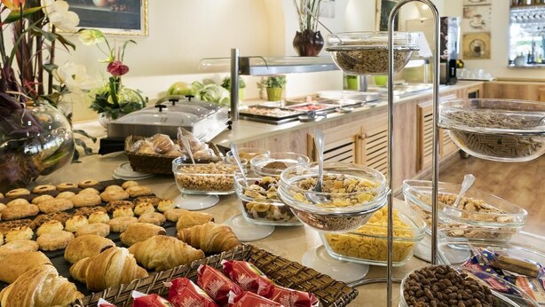 Un bufé con diversos alimentos, incluyendo pasteles, frutas y cereales.