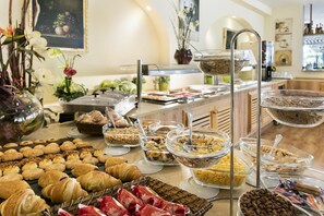 Un bufé con diversos alimentos, incluyendo pasteles, frutas y cereales.