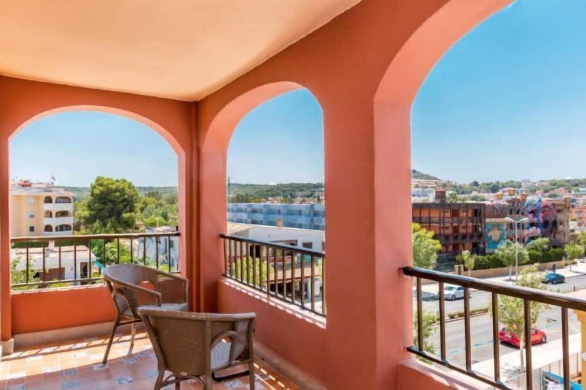 Un balcon avec deux fauteuils en osier et une vue sur le paysage urbain.