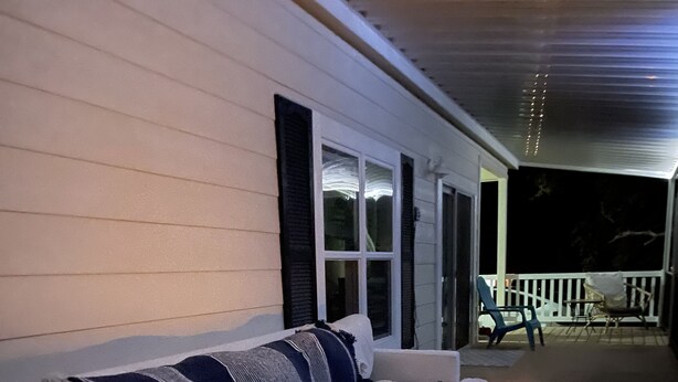 Eine überdachte Veranda mit einem weißen Sofa und einer Holzbank.