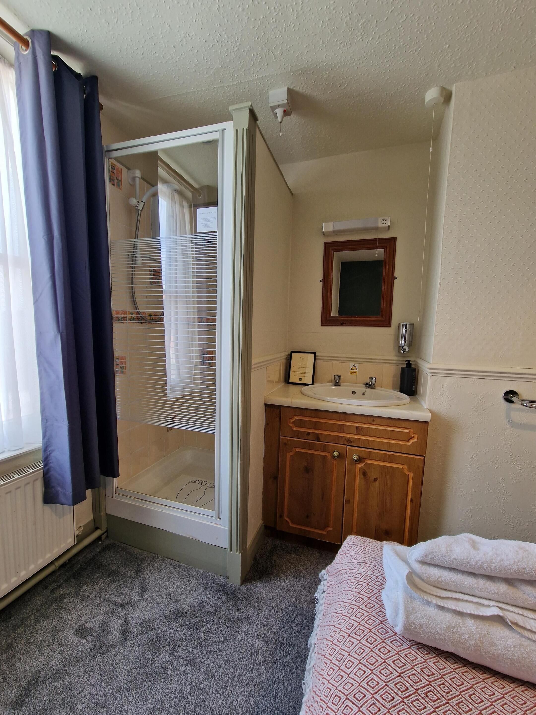 Een hotelkamer met een douche, wastafel en een bed.