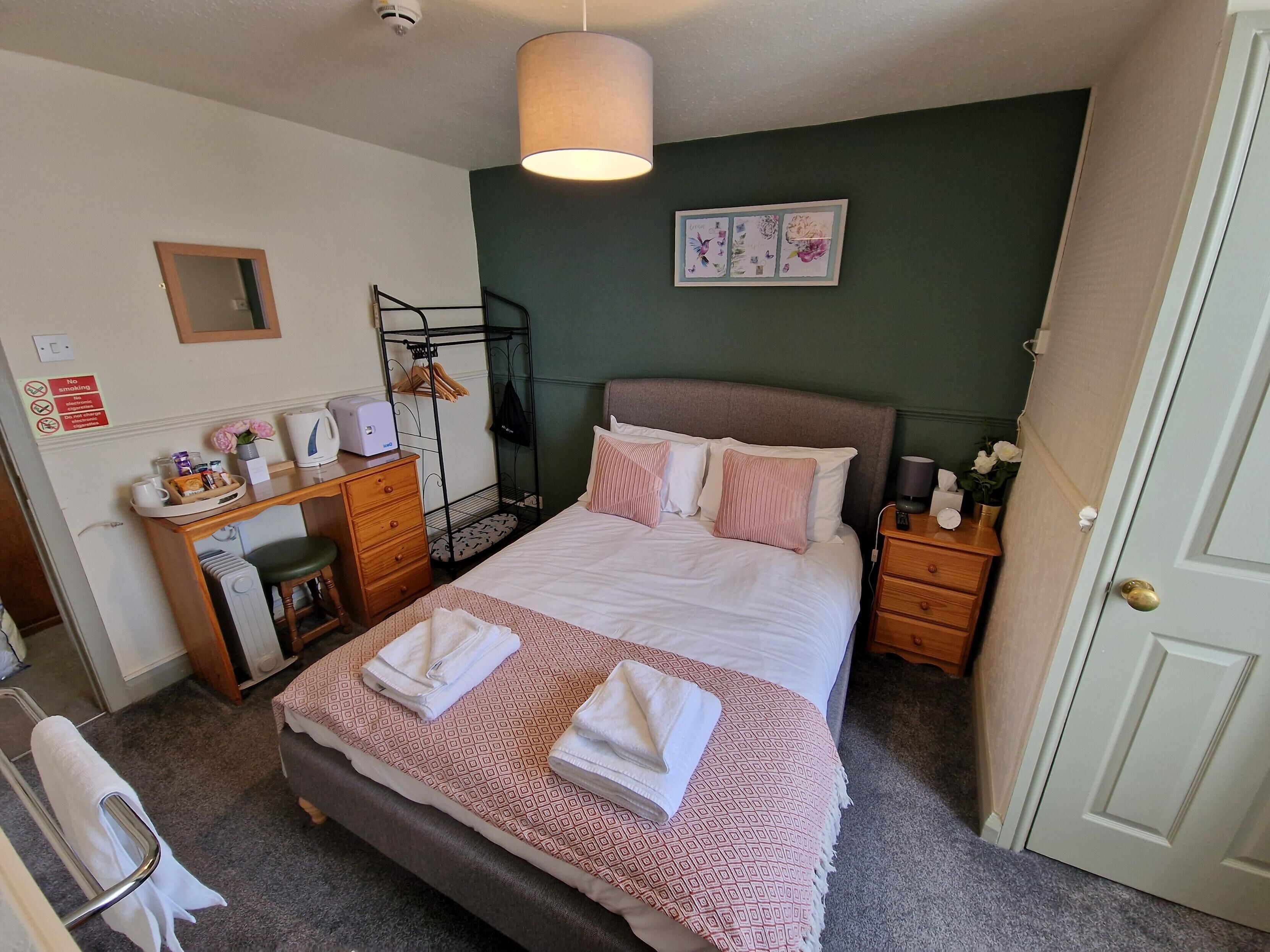 A neatly arranged hotel room with a bed, bedside tables, a desk, and a chair.