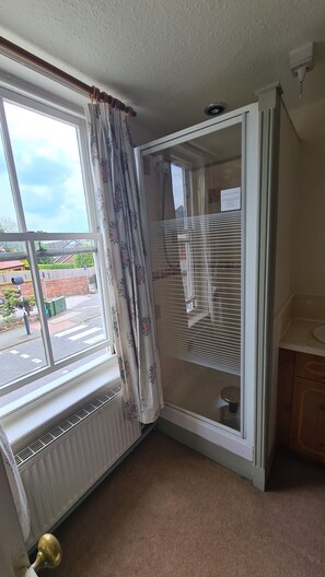 A corner room with a window, radiator, and a door with a mirror. - The Foresters Arms (Tarporley)