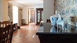 A dining area with a stone wall, a black table, and two blue and white horse-shaped vases. - Nel Cuore Della Sicilia la tua Casa Vacanze Full Optional (Tortorici)