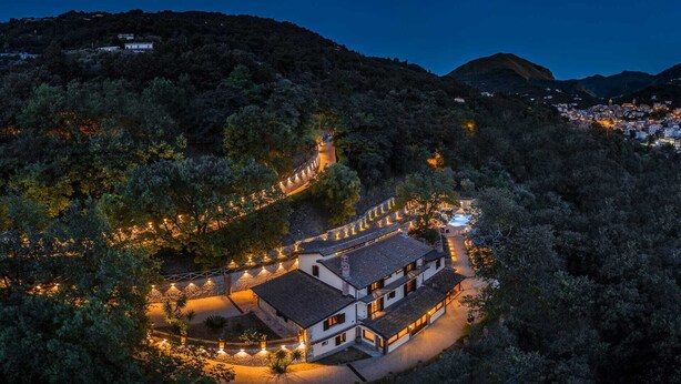An aerial view of a hillside property with a lit pathway leading to a building with multiple windows and a tiled roof. - Nel Cuore Della Sicilia la tua Casa Vacanze Full Optional (Tortorici)