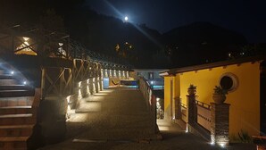 A staircase leading to a building with a yellow facade, a metal bridge, and a night sky with a visible moon. - Nel Cuore Della Sicilia la tua Casa Vacanze Full Optional (Tortorici)
