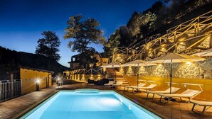 A swimming pool with lounge chairs and umbrellas, surrounded by stone walls and trees. - Nel Cuore Della Sicilia la tua Casa Vacanze Full Optional (Tortorici)
