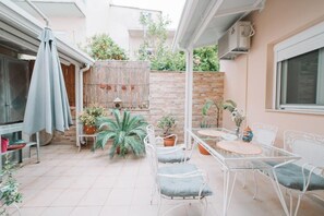 A patio area with a table and chairs, surrounded by potted plants and a bamboo fence. - Debbie's House (Kalamata)