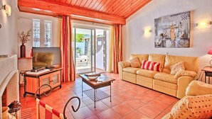 Un salon avec un plafond en bois, un canapé, une télévision et une table sur laquelle est posé un vase.
