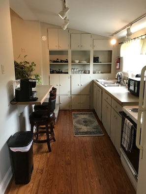 Compact kitchen with dishwasher, coffee machine, and sink.