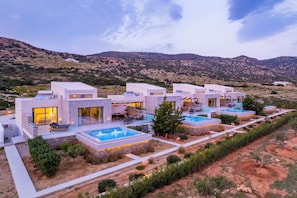 A modern resort with multiple villas, outdoor pools, and a mountainous backdrop.