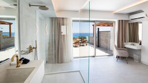 Ein modernes Badezimmer mit einer großzügigen Glasdusche, einem Waschtisch und Meerblick.