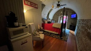 A cozy room with a bed, a chair, a microwave, and a wine cellar sign. - Unique wine cellar suite in the heart of Downtown Hermann! (Hermann)