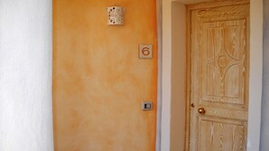Una puerta con panel de madera y un letrero con el número 6 en la pared.