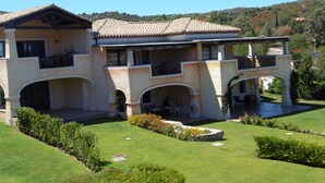 Una casa grande de dos pisos con tejado de tejas, varios balcones y un jardín bien cuidado.