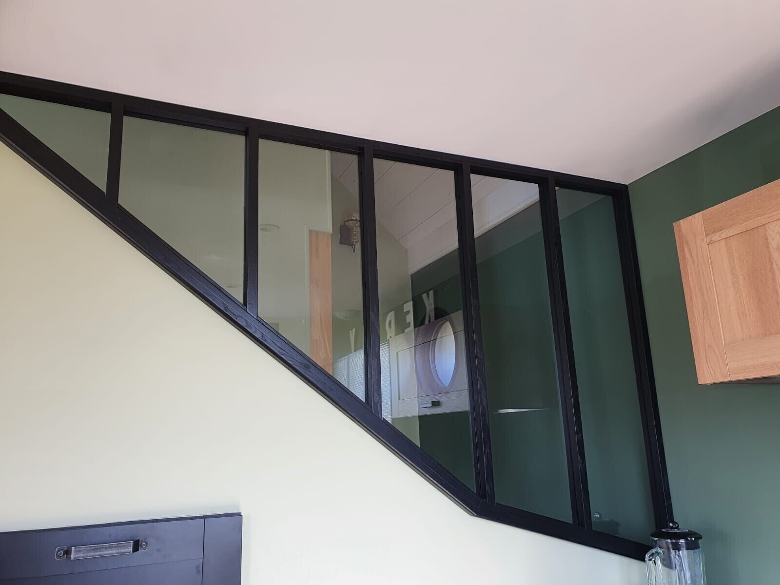 A staircase with black railings and a green wall.