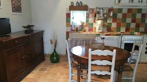 Une cuisine équipée d’une table à manger, de chaises, d’une machine à café et d’une cuisinière.