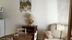 Un coin repas comprenant une table ronde en bois, des chaises, un canapé, une lampe et une fenêtre fixée au mur, offrant une vue sur la verdure.