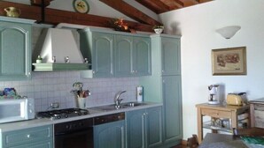 Une cuisine avec des meubles de couleur bleu clair, une cuisinière, un évier et une petite table avec une radio.