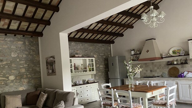 Un salon confortable avec un canapé et des fauteuils, une table à manger et un coin cuisine équipé d’un réfrigérateur et de placards.