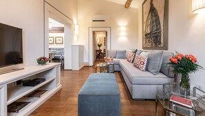 Una sala de estar moderna con sofá, reposapiés y mueble de entretenimiento.
