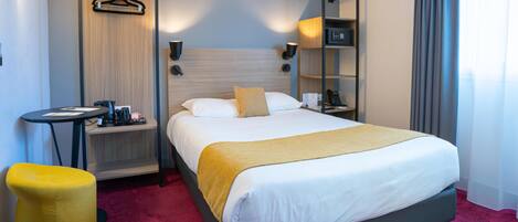 A hotel room with a bed, bedside table, hanging clothes rack, air conditioning unit, and a small stool.