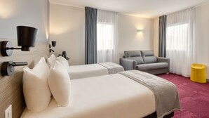 A hotel room with two beds, a sofa, a yellow ottoman, and a TV mounted on the wall. - Sure Hotel by Best Western Les Portes de Montauban (Bressols)