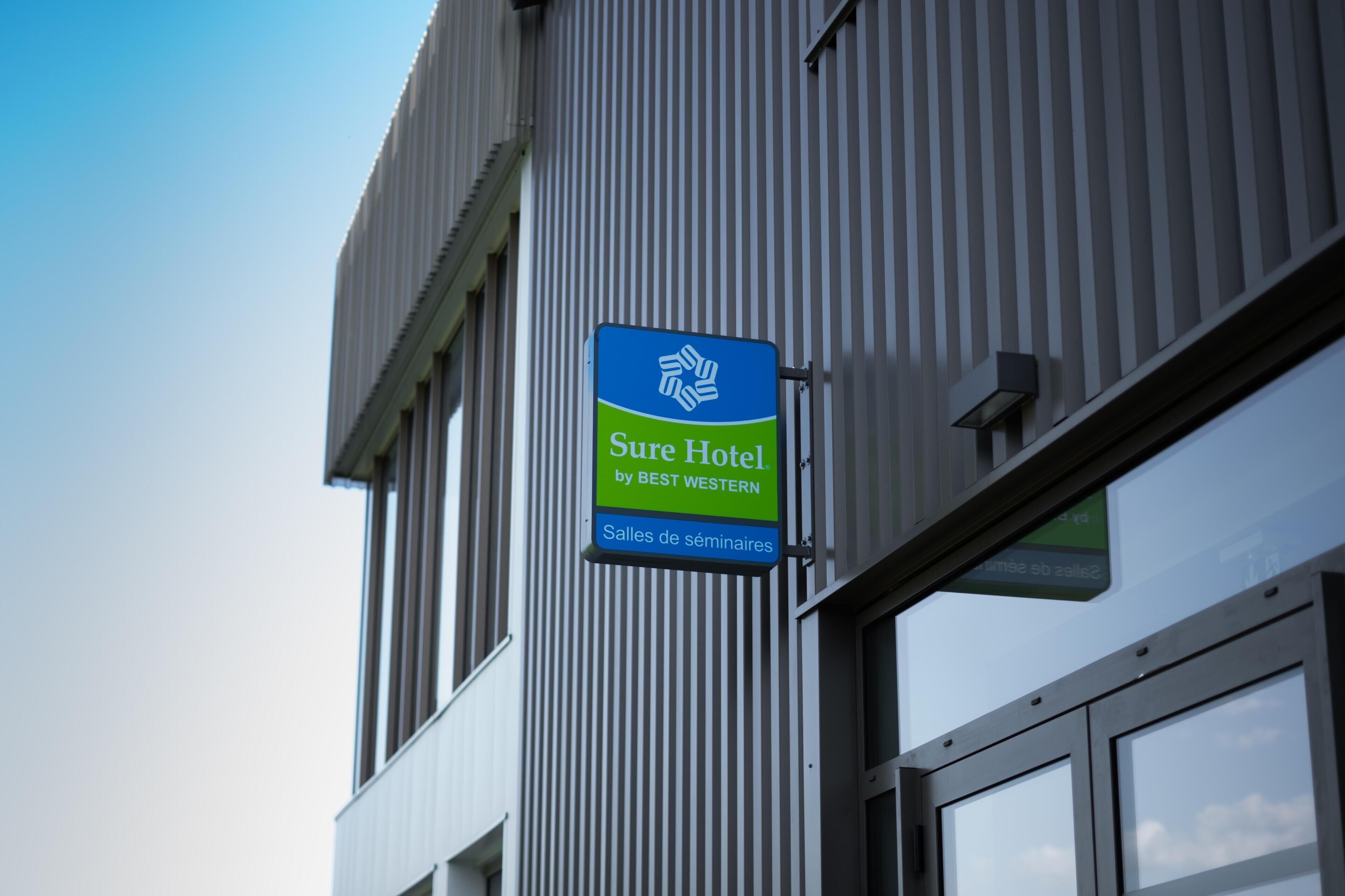 A sign for a hotel named 'Sure Hotel by BEST WESTERN' with a logo and text indicating seminar rooms.