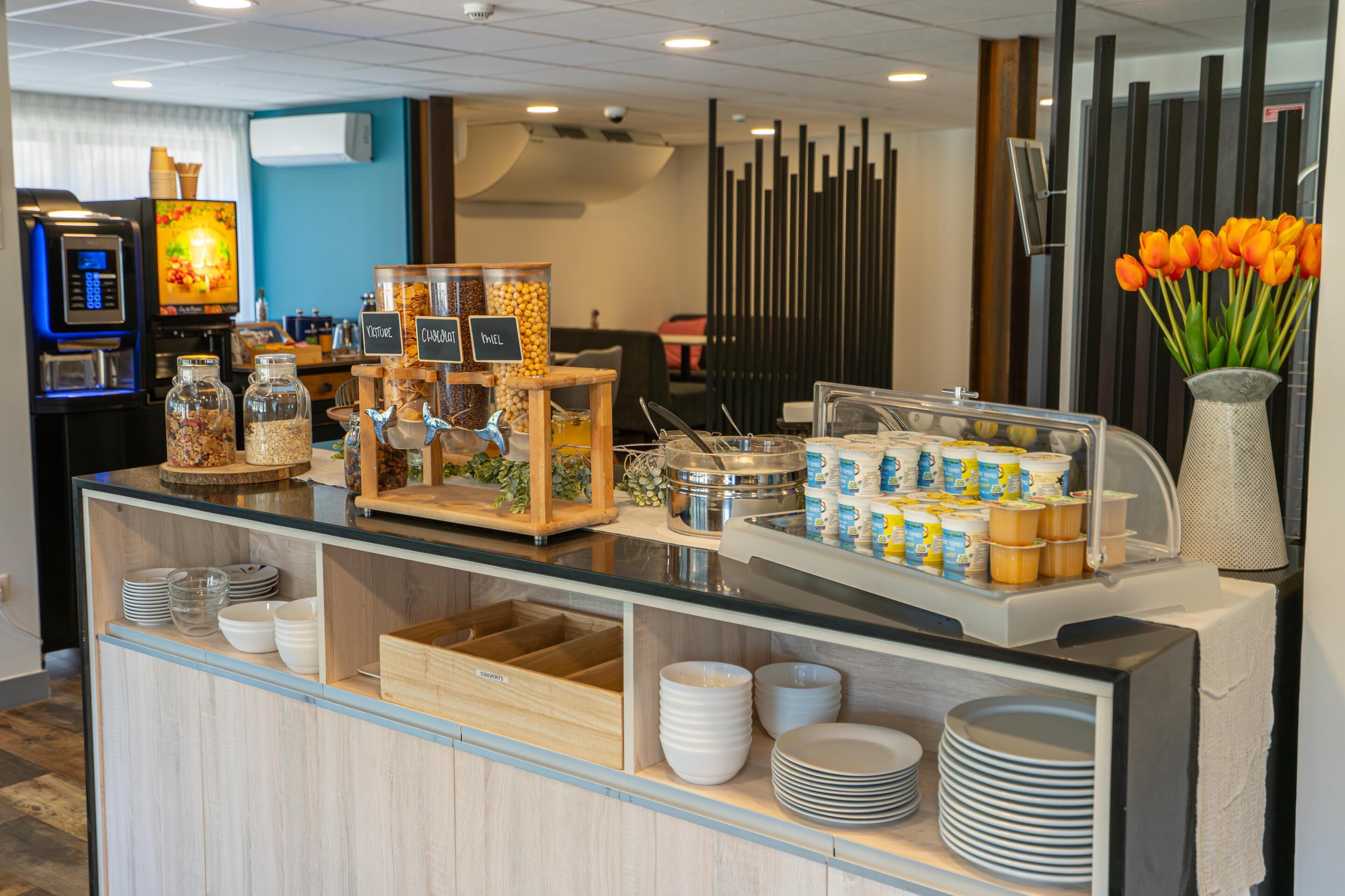 A buffet area with various food items, a coffee machine, and a vase with tulips.