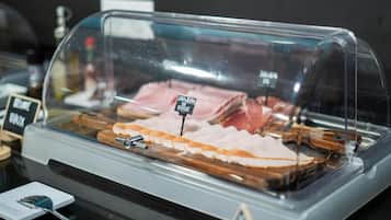 A glass display case with various meats, including ham and bacon, and a sign indicating 'Jambon de Vie'.