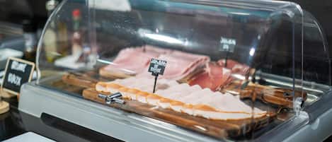 A glass display case with various meats, including ham and bacon, and a sign indicating 'Jambon de Vie'.