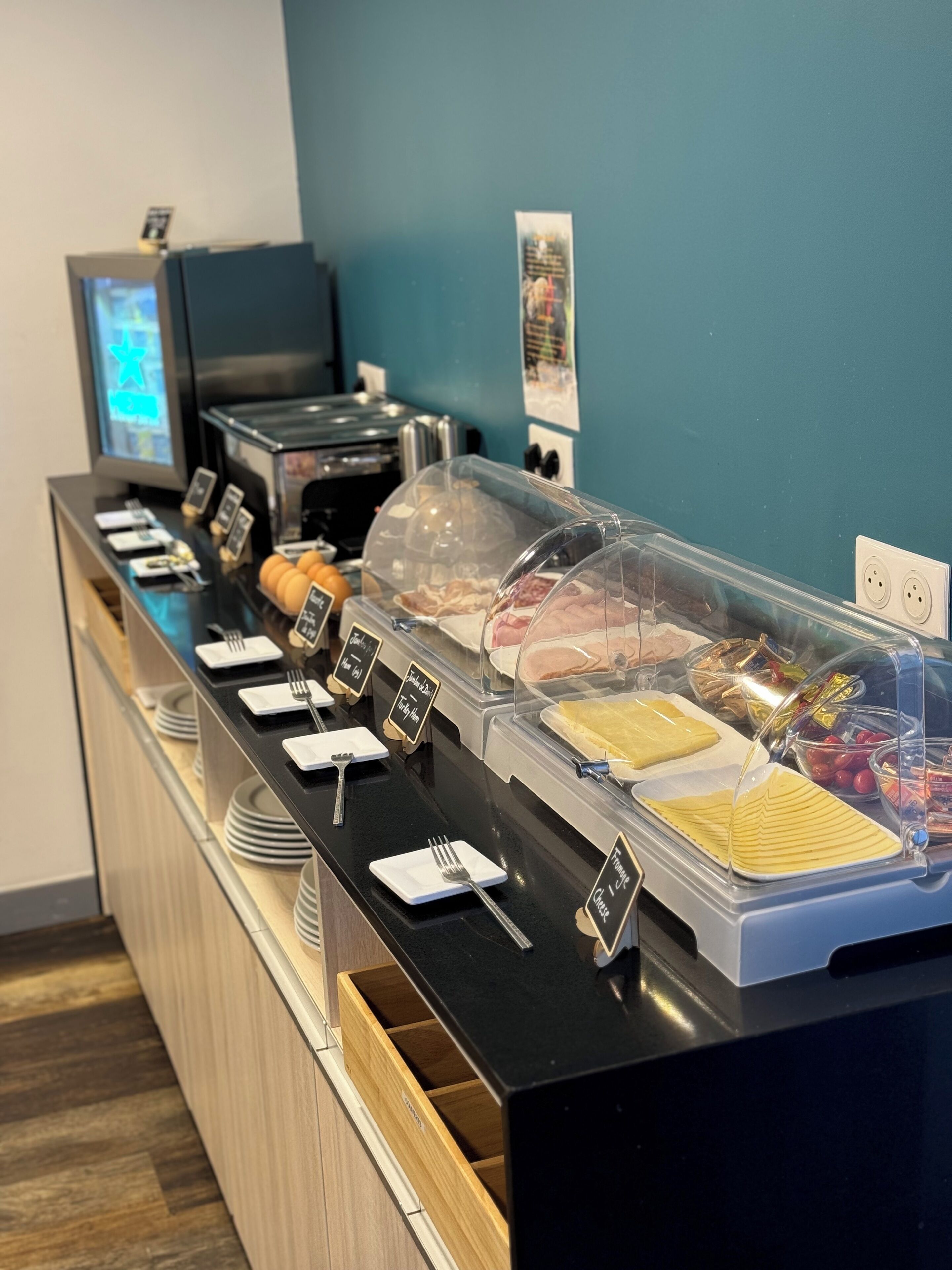 Un mostrador de buffet amb diversos aliments, una màquina de cafè i un panell de control digital.