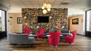 A lobby with a floral wallpaper, a flat-screen TV, and modern seating including red and grey chairs. - Sure Hotel by Best Western Les Portes de Montauban (Bressols)