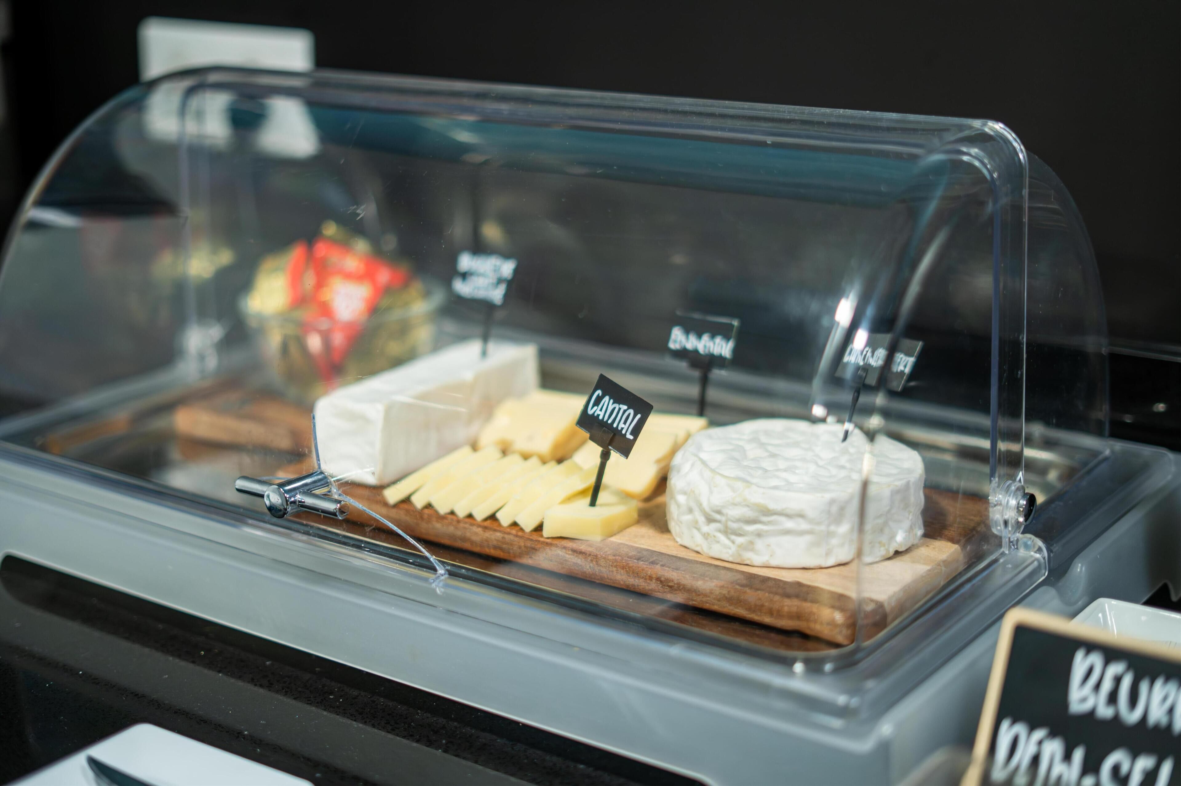 A cheese display with labels 'CANTAL' and 'BEUREM' in a glass case.