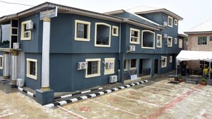 A multi-story building with a dark facade, multiple windows, and air conditioning units. - Beautiful 1 Bed, Living Room in a Hotel Penthouse (Lekki)
