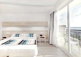 Una habitación de hotel con una cama grande, una mesita de noche, una silla y un balcón con vistas a la ciudad.