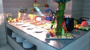 Uma área de buffet com diversos alimentos e uma decoração central com abacaxi.
