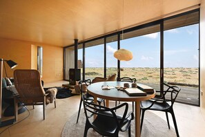 A modern interior with a round table, chairs, a fireplace, and large windows offering a desert view.