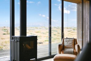 A room with a large window, a fireplace, and a leather chair.