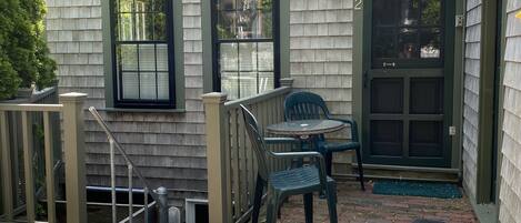 A house with a brick patio, two outdoor chairs, and a small table.