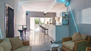 A modern hotel lobby with a bar area, wicker furniture, and a view of the outdoors. - Marigna (Ibiza Town)