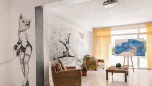 A spacious lobby with a large abstract mural, comfortable seating, and a painting on display. - Marigna (Ibiza Town)