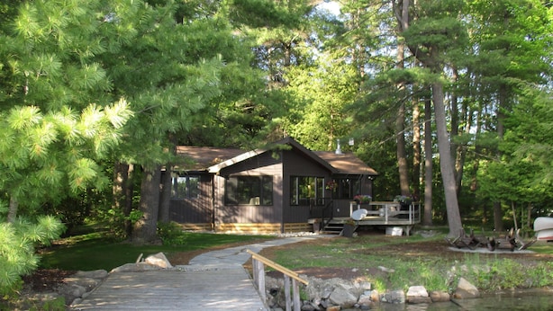 A wooden dock leading to a cabin surrounded by trees.