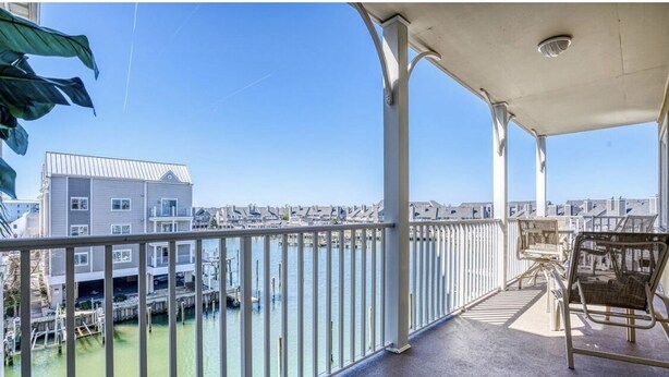 A balcony with a view of a marina and buildings. - Luxury Waterfront Condo  (Ocean City)