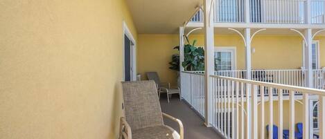 A balcony with a chair, a small table, and a railing.