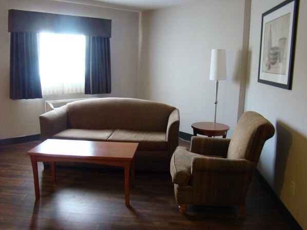 A living room with a sofa, a chair, a small table, and a floor lamp. - Quality Inn and Suites Saskatoon (Saskatoon)