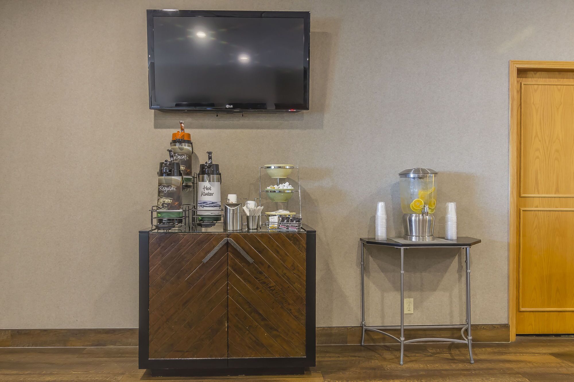 A bar area with a TV above, a coffee machine, and a drink dispenser.