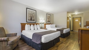 Habitación de hotel con dos camas, un escritorio, una silla y dos cuadros en la pared.