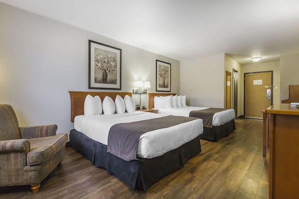 A hotel room with two beds, a desk, a chair, and two framed pictures on the wall. - Quality Inn and Suites Saskatoon (Saskatoon)