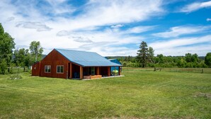 A wooden cabin with a blue roof in a grassy field. - The Cascade Mountain-View Retreat (Fort Klamath)